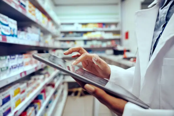 Closeup of hands of young female pharmacist checking inventory in medical store using digital tablet Farmácias têm índice de perdas abaixo da média do varejo