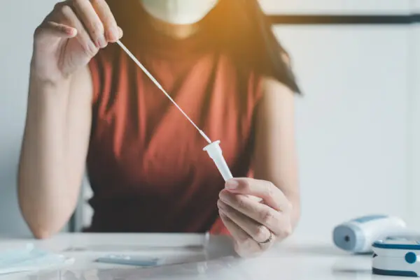 Patient woman using a covid-19 self test rapid antigen testing kit at home